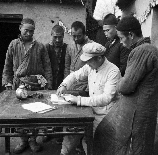 人民政府是翻身农民的靠山,支持农民彻底翻身的要求。图为某区长在农民的新田契上盖上红印。 (邹健东 摄)